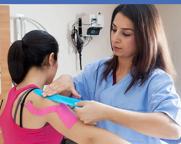 A woman is taping another person 's arm.