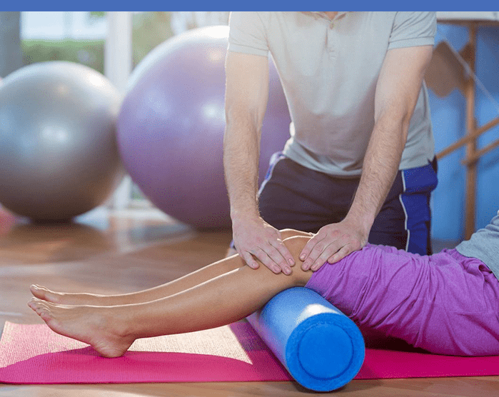 A person is rolling on the ground with a foam roller.