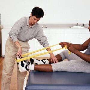 A man helping another man stretch his leg.