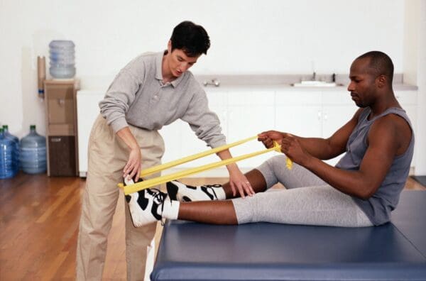 A man helping another man stretch his leg.